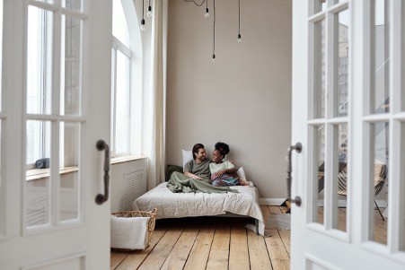 A couple on a bed in an all-white room Felony Record Hub